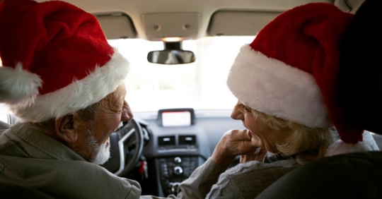 man and wife driving in Santa hats